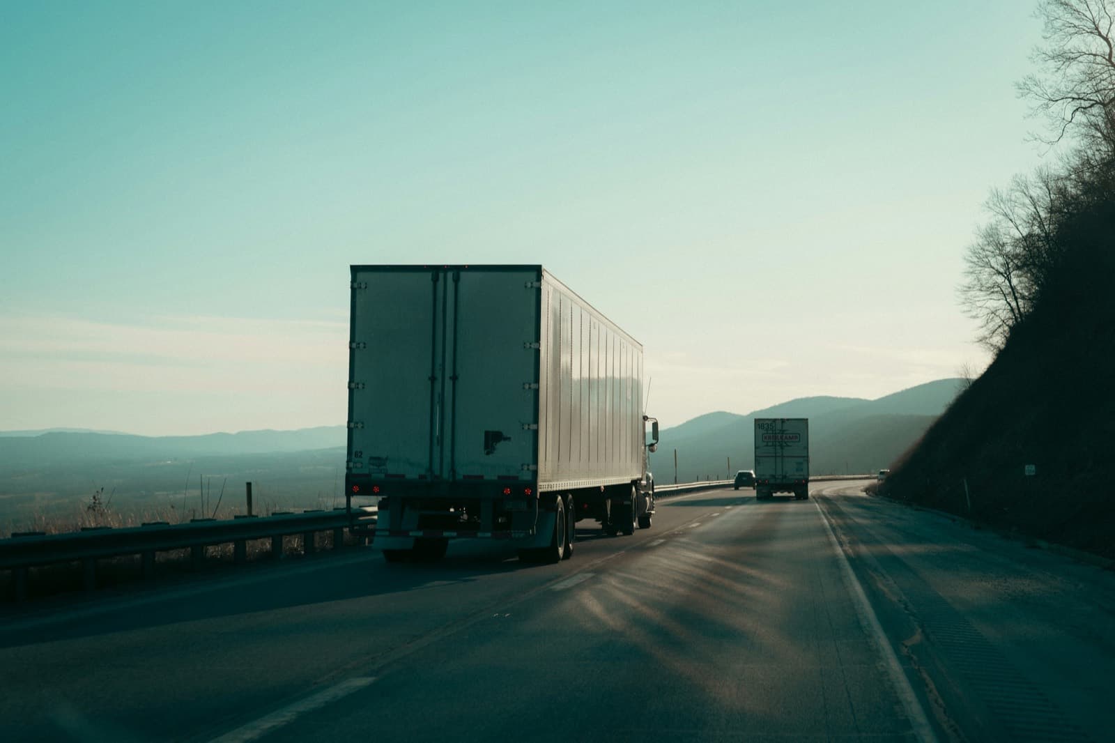Trailers on a highway heading toward hills at dawn