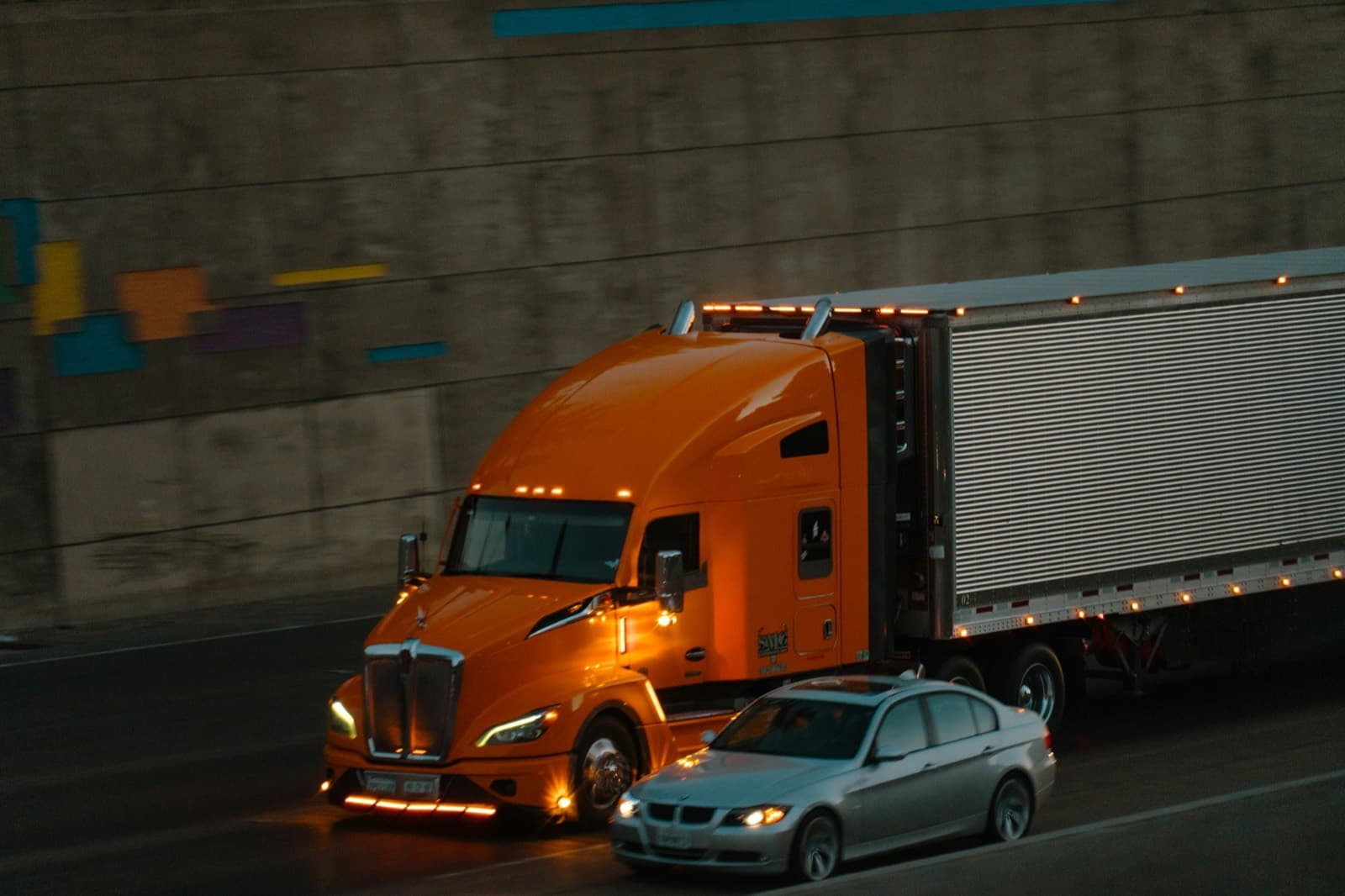 A semi truck moving at night with its lights on